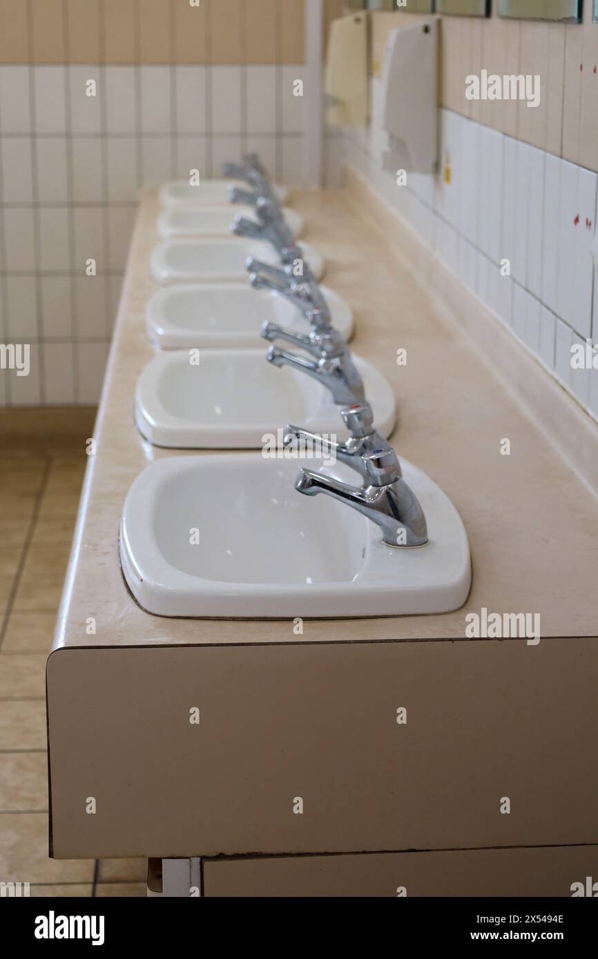 Spülen in einer Reihe in der öffentlichen Toilette in England Stockfoto