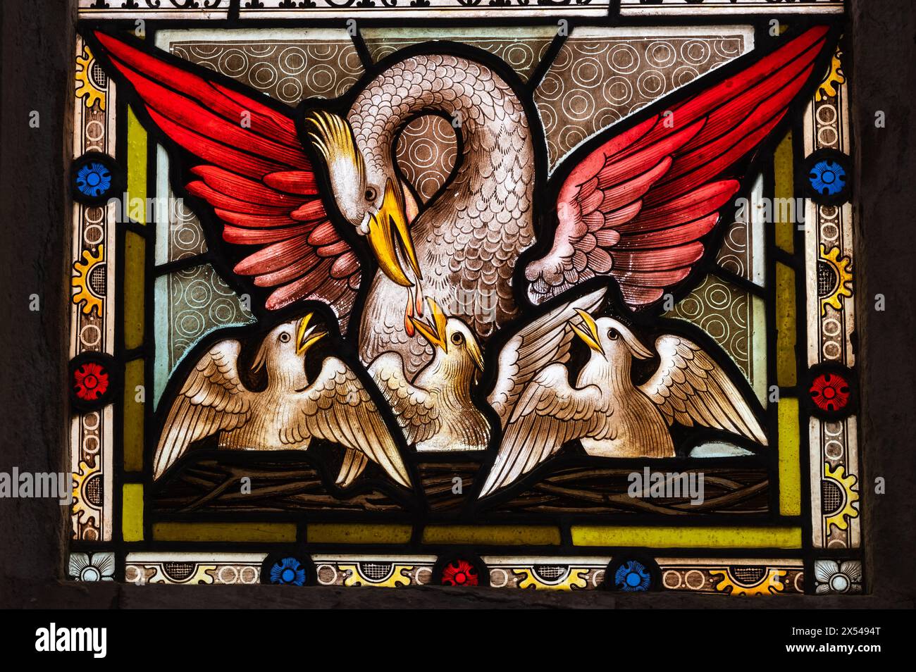 Buntglasfenster mit einem Phönix-Pelican-Hybrid mit feurigen Flügeln, die seine Jungen mit Blut aus der Brust füttern Stockfoto