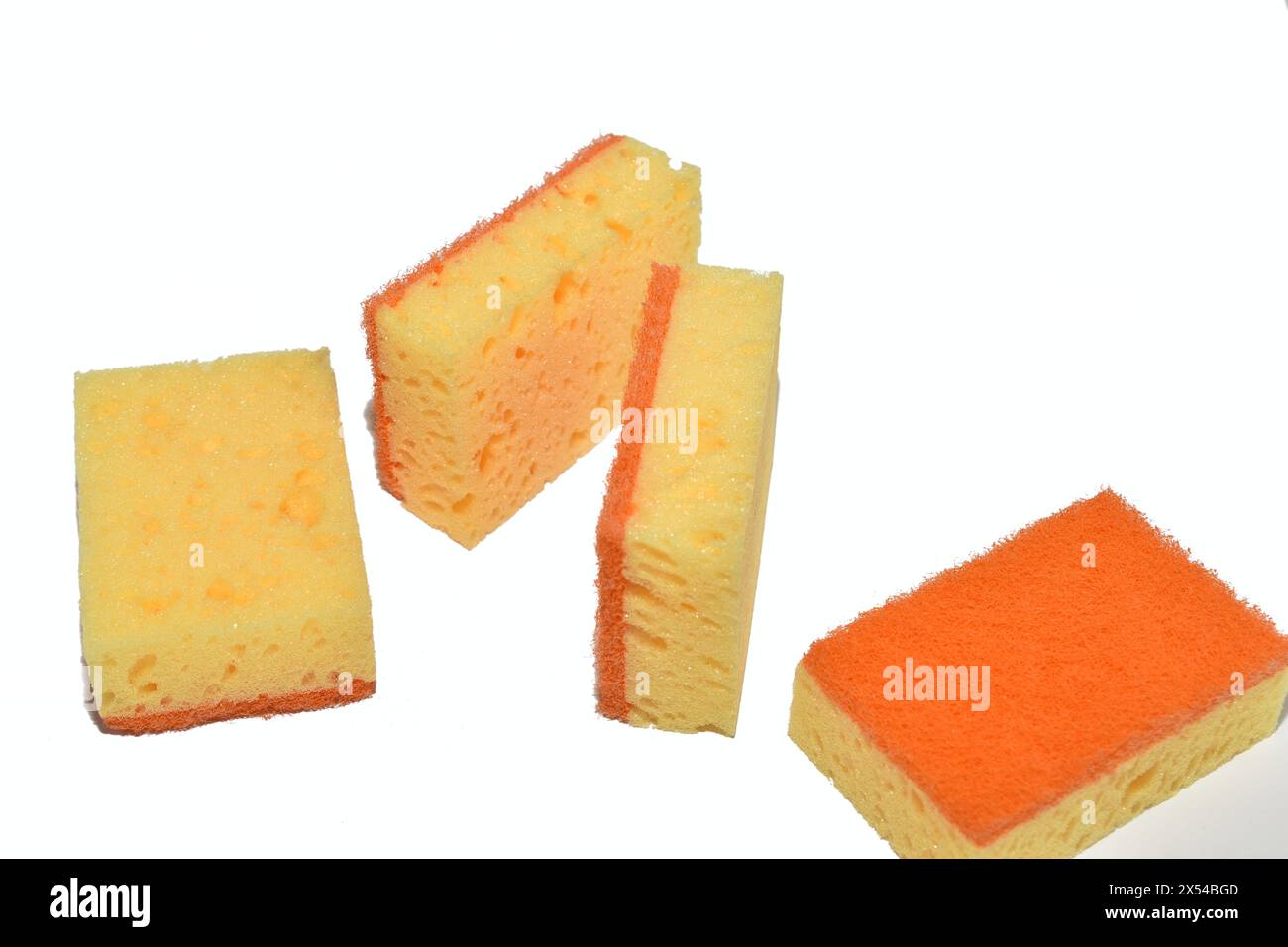 Orangefarbene Küchenschwämme liegen chaotisch auf weißem Hintergrund. Stockfoto