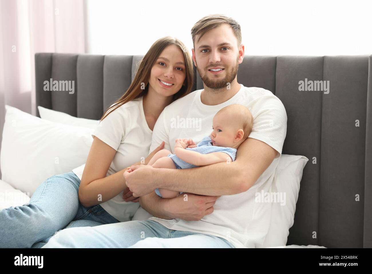 Glückliche Familie. Eltern mit ihrem süßen Baby im Bett drinnen Stockfoto