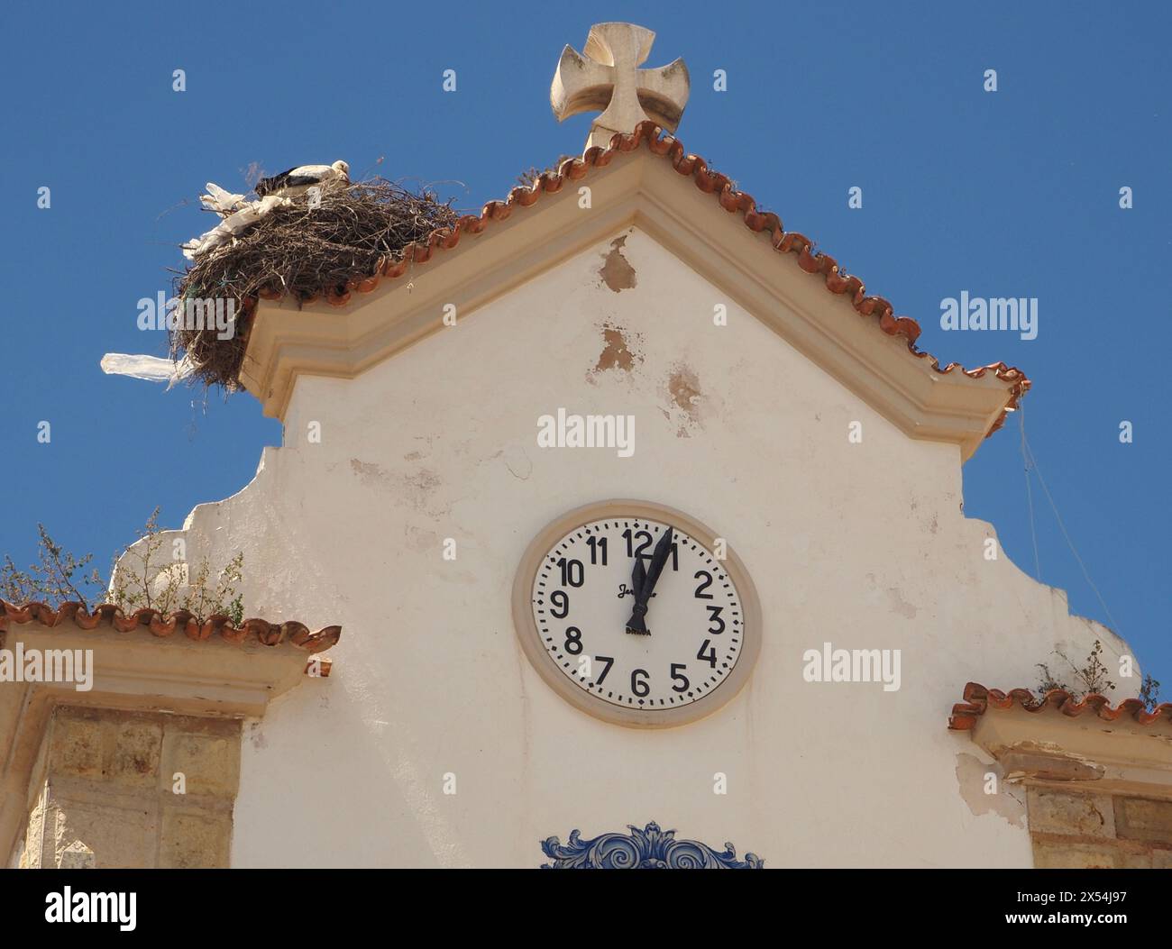 Storchennest, in dem verworfene Kunststofffolien verwendet wurden. Auf dem Dach der Kapelle in Olhão, Algarve, Portugal. Plastik und Tierwelt. Stockfoto