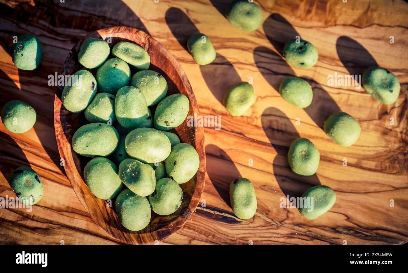 Wasabi, japanischer Meerrettich (Eutrema japonica, Wasabia japonica), Wasabi-Nüsse in einer Holzschale, geröstete Erdnüsse, beschichtet mit Wasabi Stockfoto