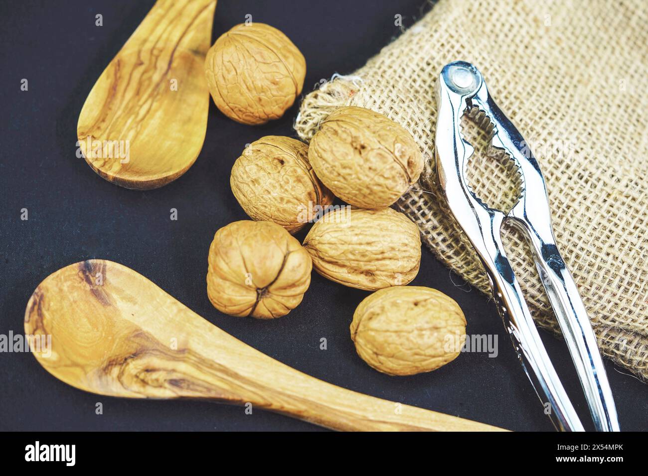 Walnuss (Juglans regia), Walnüsse mit Sack, Holzlöffel und Nussknacker Stockfoto