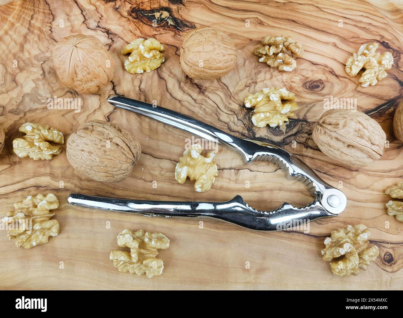 Walnuss (Juglans regia), Walnüsse, ganz und gerissen, mit Nussknacker Stockfoto