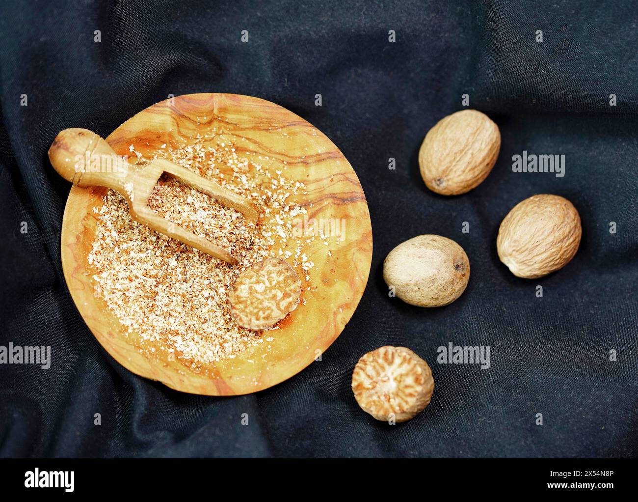 Muskatnuss, Muskatblüte (Myristica duftet), Muskatnuss auf einem Holzteller mit einem Holzlöffel. Ganz und gerieben Stockfoto