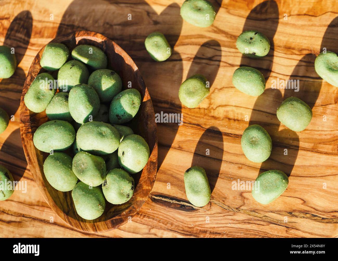 Wasabi, japanischer Meerrettich (Eutrema japonica, Wasabia japonica), Wasabi-Nüsse in einer Holzschale, geröstete Erdnüsse, beschichtet mit Wasabi Stockfoto