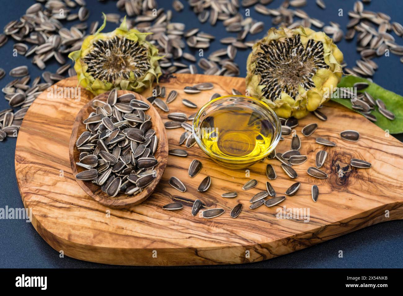 Sonnenblumenkerne in einer Holzschale auf einem Brett mit einer Glasschale und Sonnenblumenöl Stockfoto