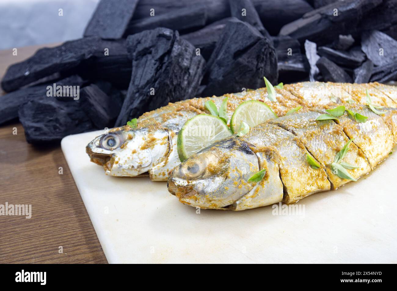 Fisch BBQ. Marinierter Fisch mit Salz Pfeffer, grünem Chili und Kurkumapulver. Holzkohle und Holzkohle im Hintergrund. Zubereitung von Fisch. Stockfoto