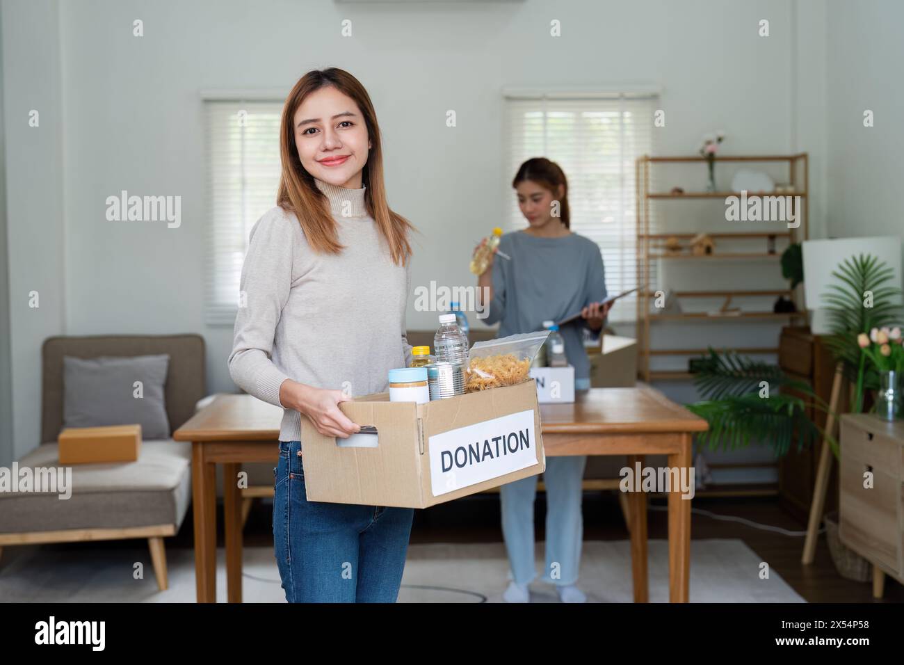 Wohltätigkeitskonzept, Spende und Freiwilligentätigkeit. Freiwillige bereiten eine Lebensmittelbox mit Lebensmitteln vor, um sie an arme Menschen zu spenden, Katastrophenopfer zu Hause Stockfoto