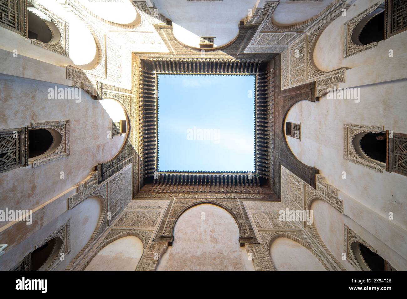 Ein ruhiger Blick in den Himmel, eingerahmt von der kunstvollen Architektur von Cherratine Madrasa, Fès, Marokko Stockfoto