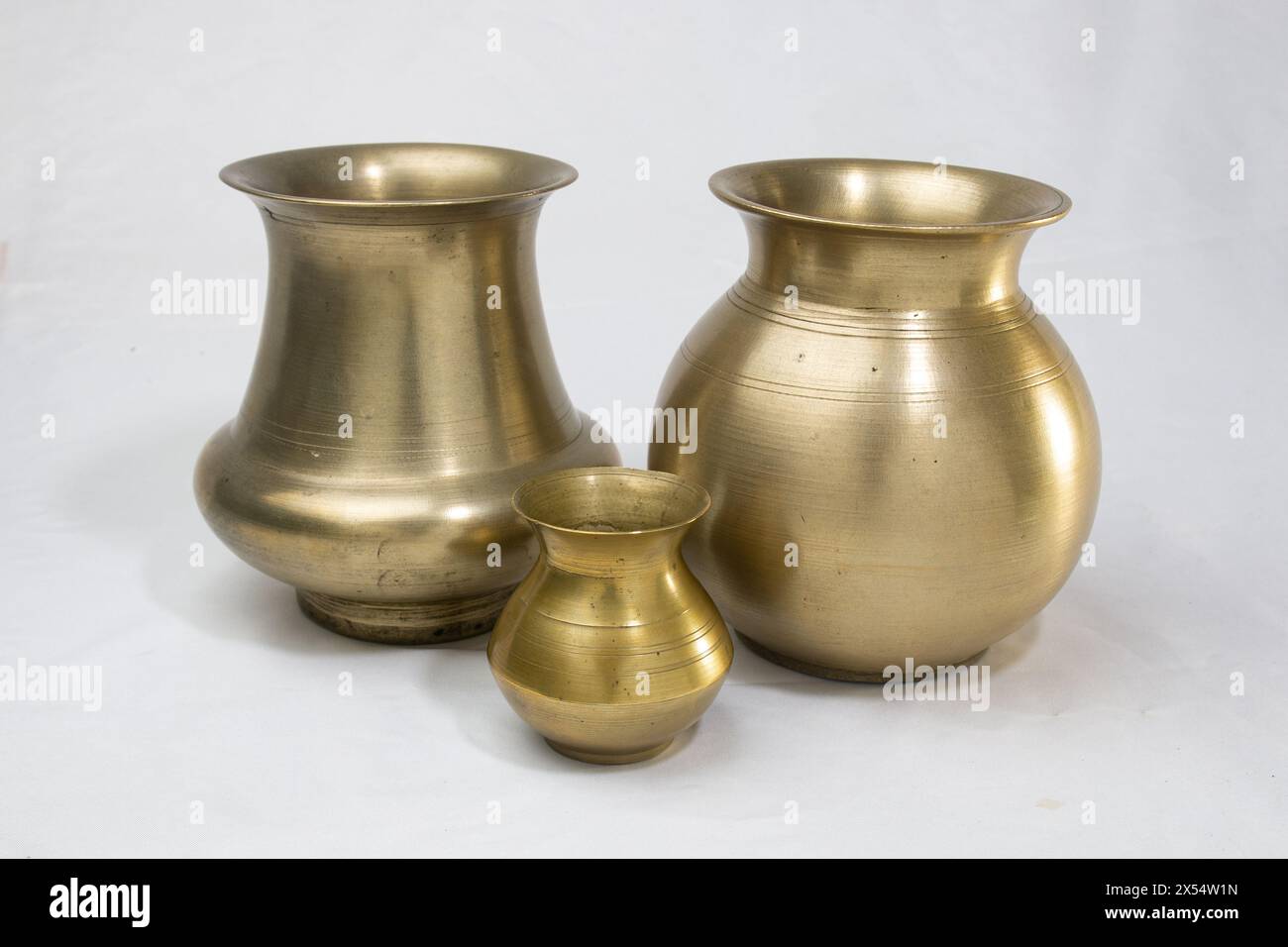 Leere goldene Messinggefäße, die als Wassertopf für traditionelle Rituale während religiöser hindufeste verwendet werden, isoliert auf weißem Hintergrund. Stockfoto