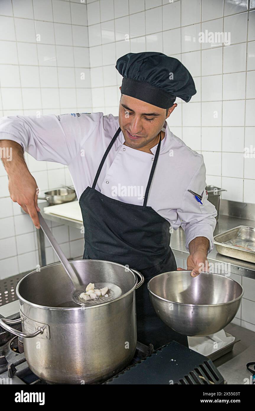 Küchenhelfer, der Fischstücke aus einem Topf zieht Stockfoto