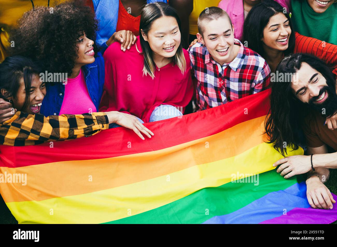 Verschiedene Menschen haben Spaß, die LGBT-Regenbogenfahne im Freien zu halten - multirassische Freunde haben Spaß zusammen nach dem Gay Pride Event Stockfoto
