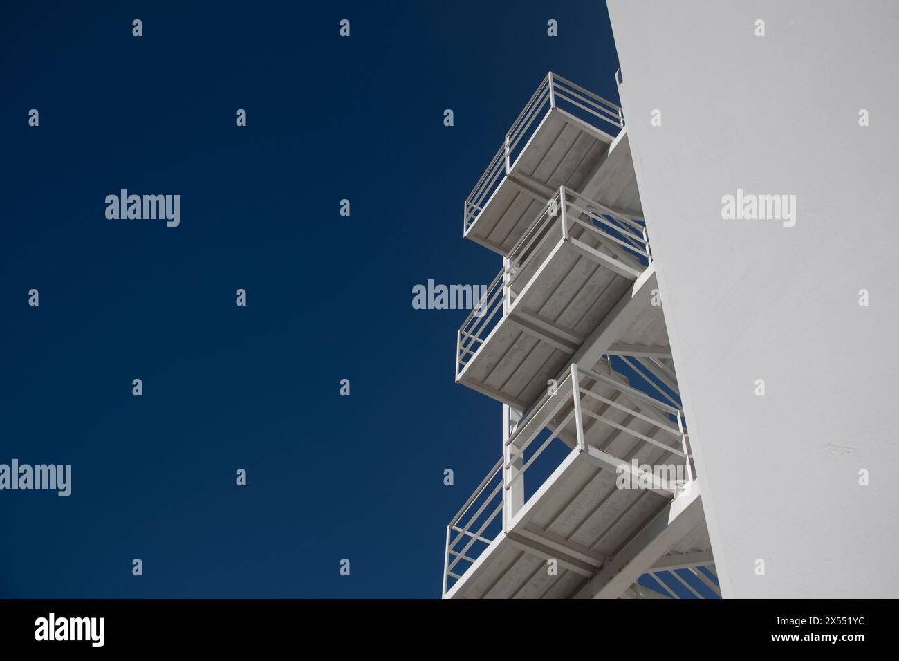 Modernes weißes Betongebäude mit einer Außentreppe aus Metall mit blauem Himmel Stockfoto