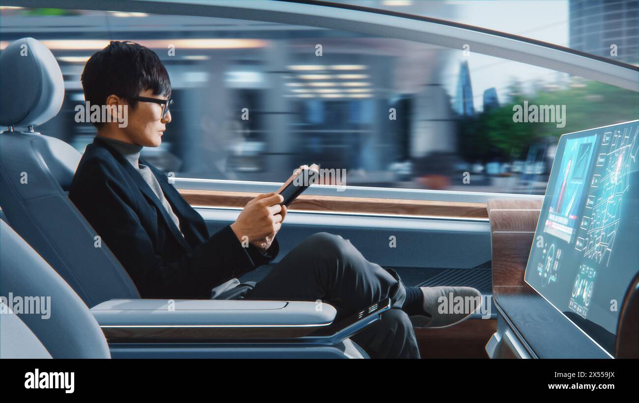 Futuristisches Konzept: Schöner, stilvoller japanischer Geschäftsmann in Brille, der Notizbuch liest und Nachrichten auf dem Augmented Reality Screen ansieht, während er in einem autonomen, selbstfahrenden emissionsfreien Auto sitzt. Stockfoto