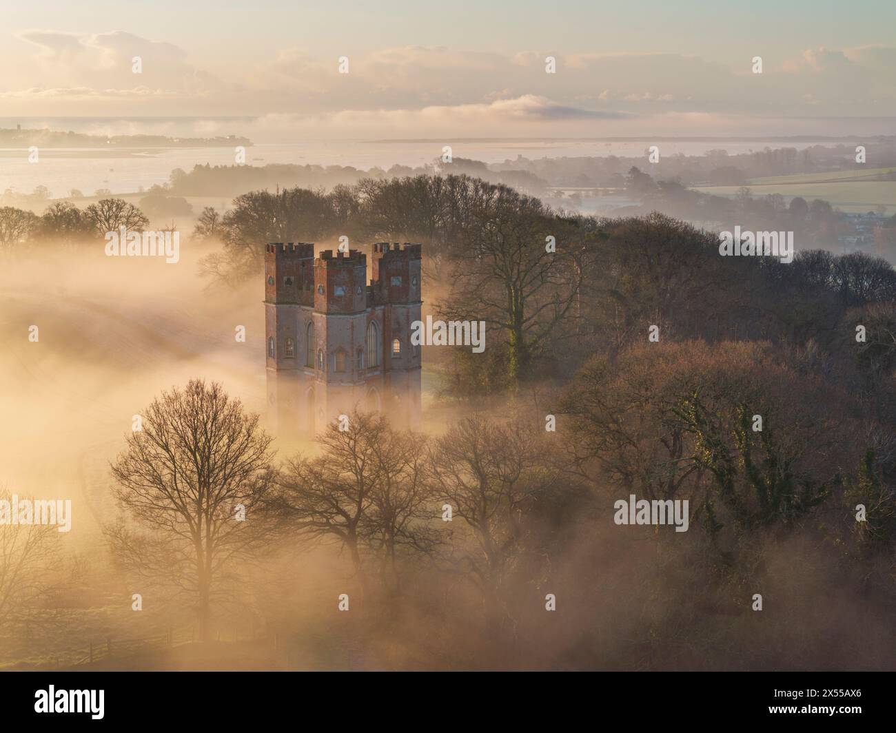 Morgennebel umgibt den Belvedere-Turm bei Sonnenaufgang an einem Wintermorgen, Powderham Castle, Devon, England. Winter (März) 2024. Stockfoto