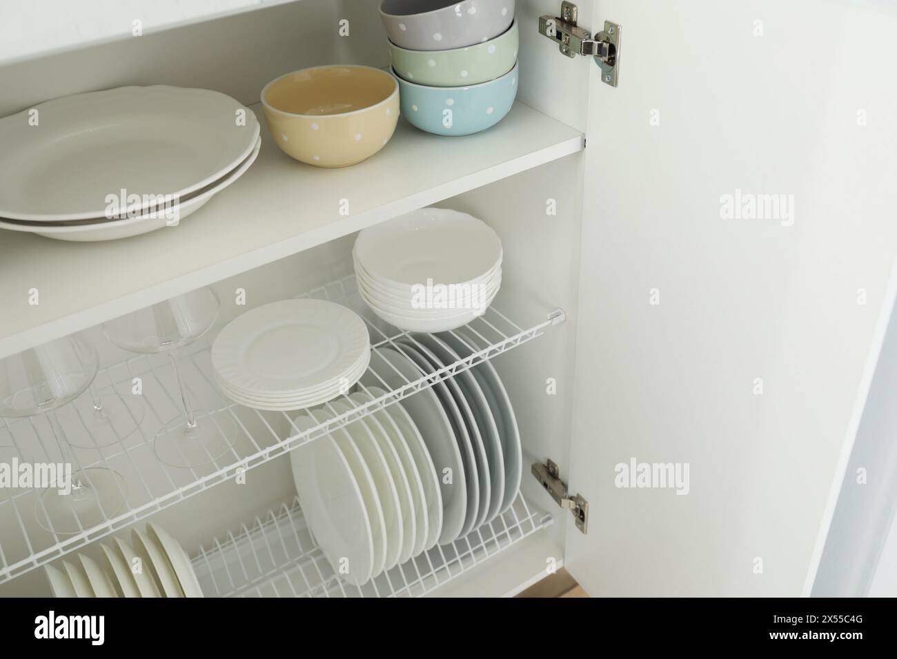 Reinigen Sie Teller, Schüsseln und Gläser auf den Regalen im Schrank im Innenbereich Stockfoto