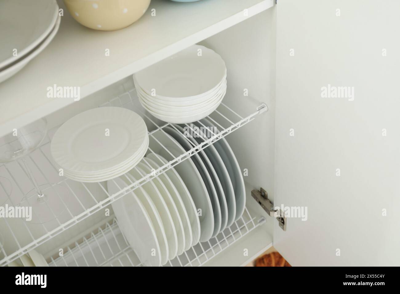 Reinigen Sie Teller, Schüsseln und Glas auf den Regalen im Schrank im Innenbereich Stockfoto