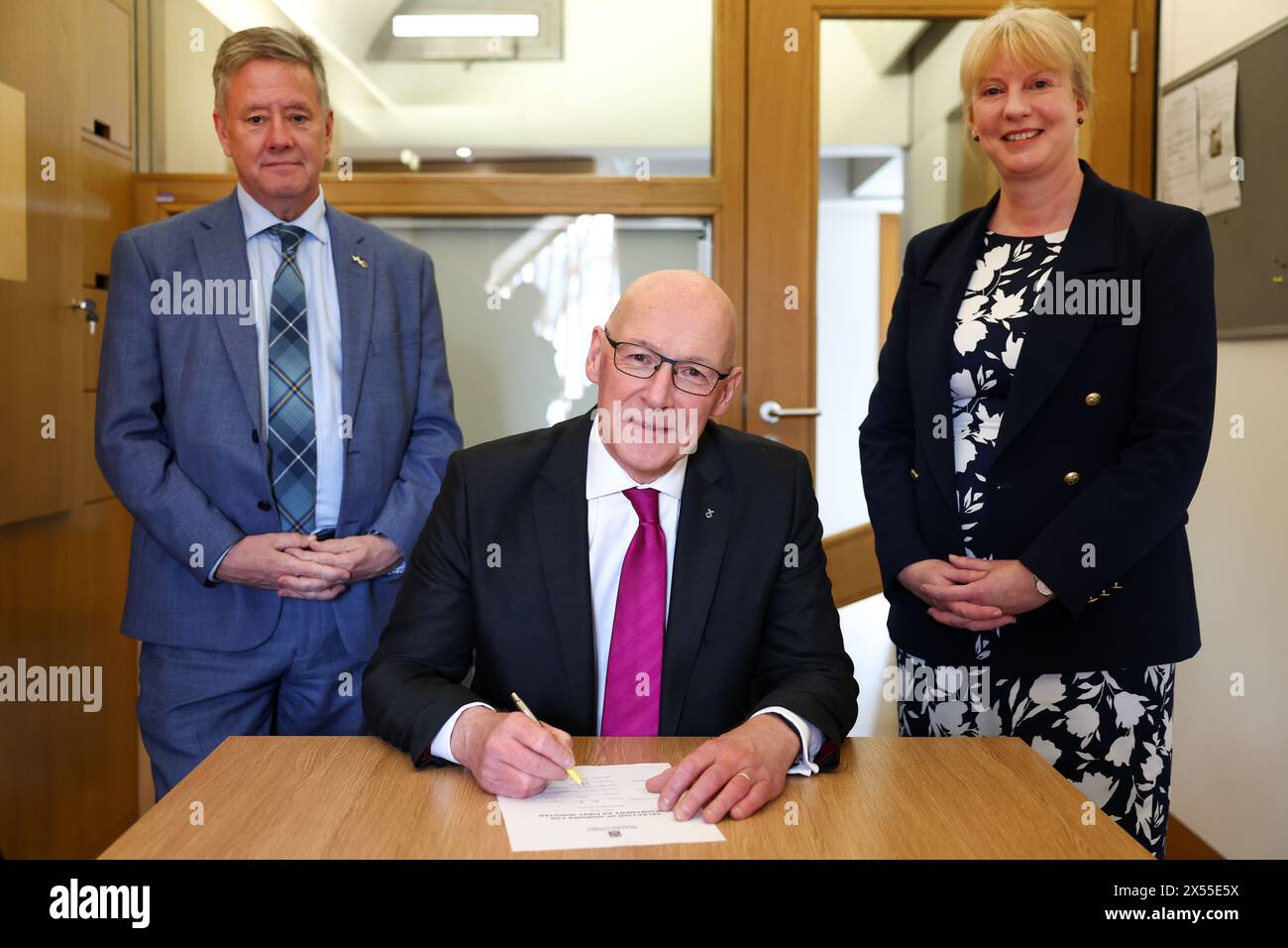 John Swinney, der Vorsitzende der New Scottish National Party (SNP), unterzeichnet sein Nominierungsschreiben zum Ersten Minister, zusammen mit seinen Befürwortern Shona Robinson (rechts) und Keith Brown, im schottischen Parlament in Edinburgh. Bilddatum: Dienstag, 7. Mai 2024. Stockfoto