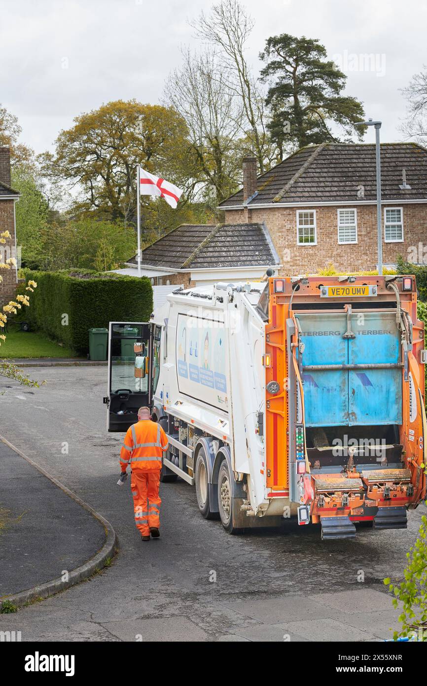 Recycler in orangefarbener Jacke und Hose neben einem zerbrechenden LKW. Stockfoto