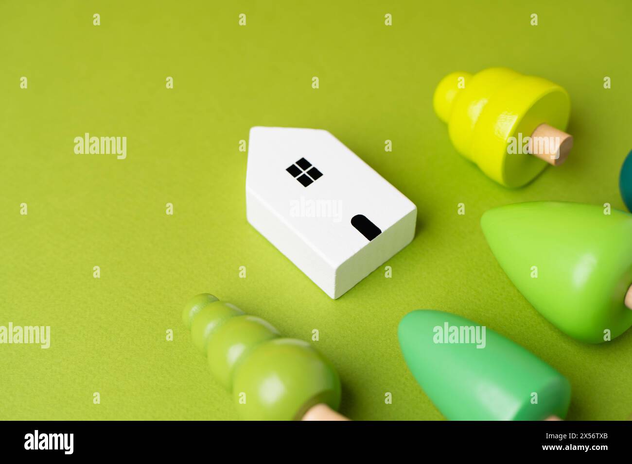 Haus und Bäume auf grünem Hintergrund. Umweltfreundlichkeit und Öko-Leben. Landschaftsdesign. Neue Richtungen für die Wohnungsentwicklung. Stockfoto