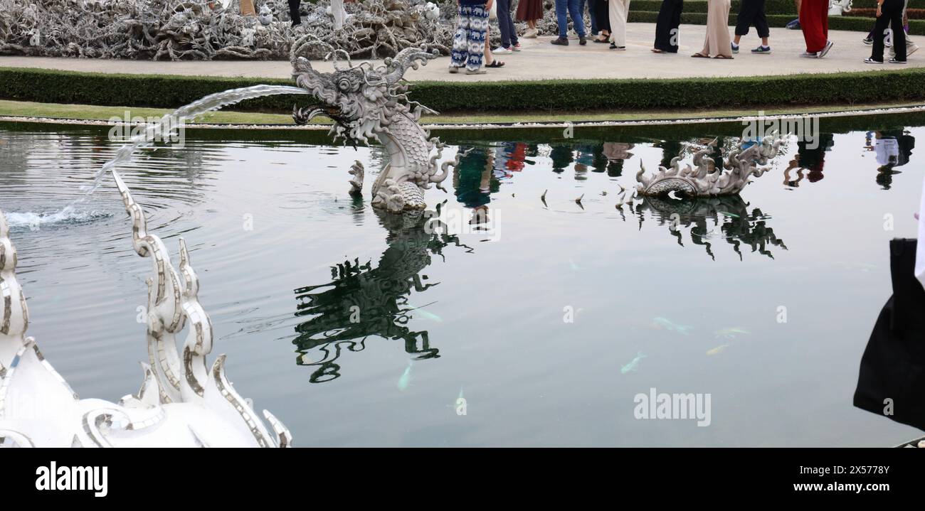 Eine Statue/Brunnen einer Seeschlange in einem Teich voller Koi vor dem Eingang zum Weißen Tempel in der Provinz Chiang Rai, Thailand Stockfoto