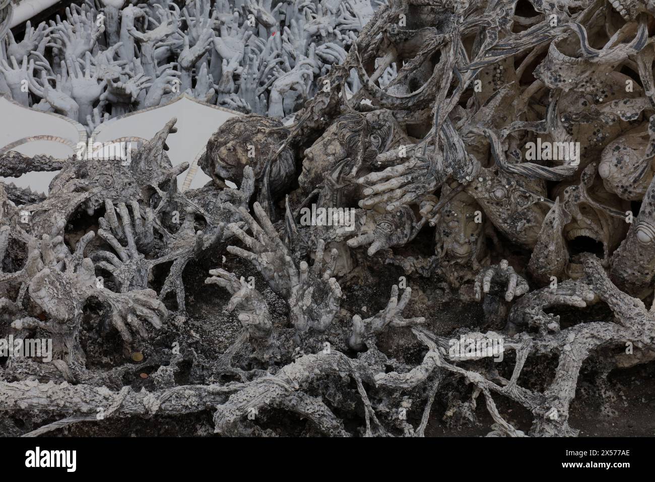 Skulpturen von Händen und Gesichtern, die nach oben am Weißen Tempel, Wat Rong Khun, in der Provinz Chiang Rai in Thailand reichen Stockfoto