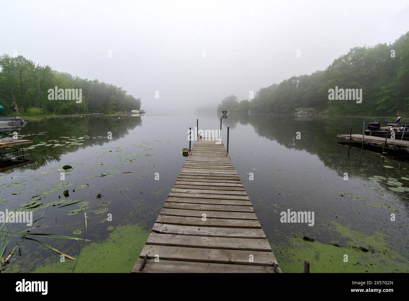 An einem nebeligen Morgen auf einem ruhigen Wisconsin-See. Fischerboot in der Ferne. Stockfoto