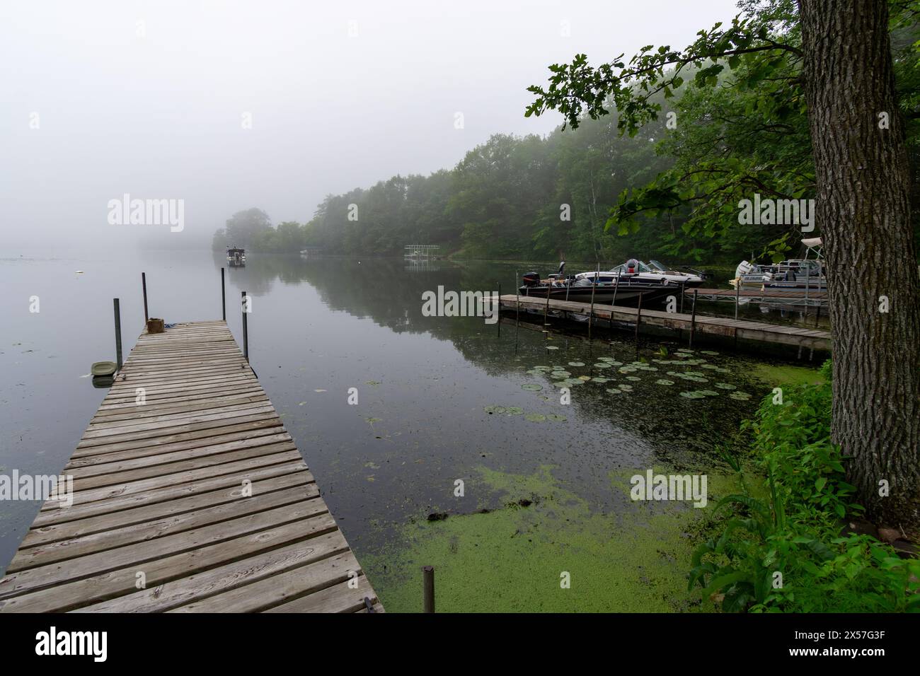 An einem nebeligen Morgen auf einem ruhigen Wisconsin-See. Fischerboot in der Ferne. Stockfoto