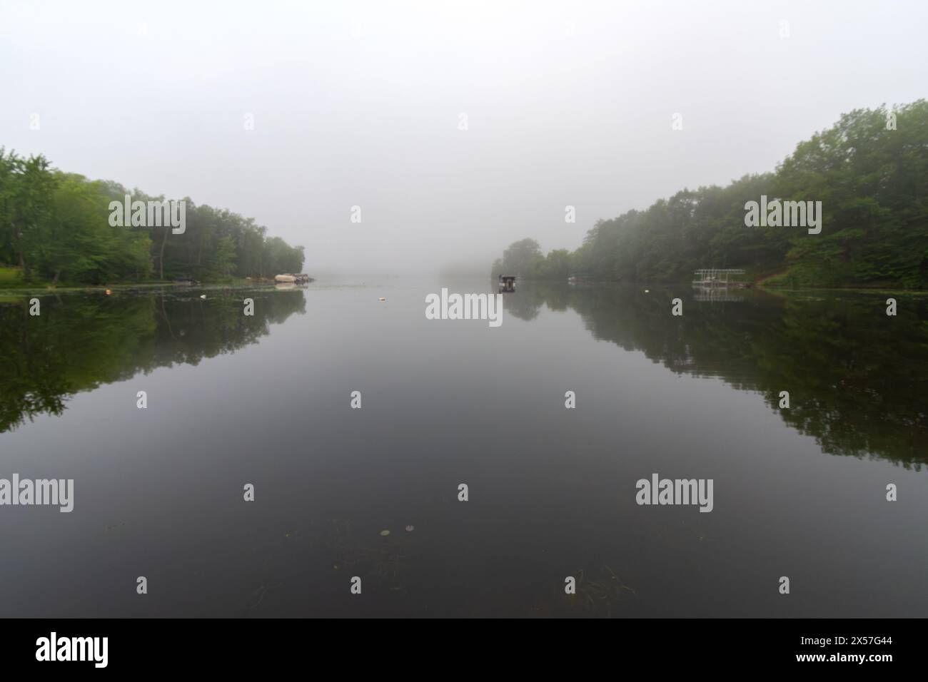 Blick auf einen ruhigen Wisconsin See an einem nebeligen Morgen. Fischerboot in der Ferne. Stockfoto