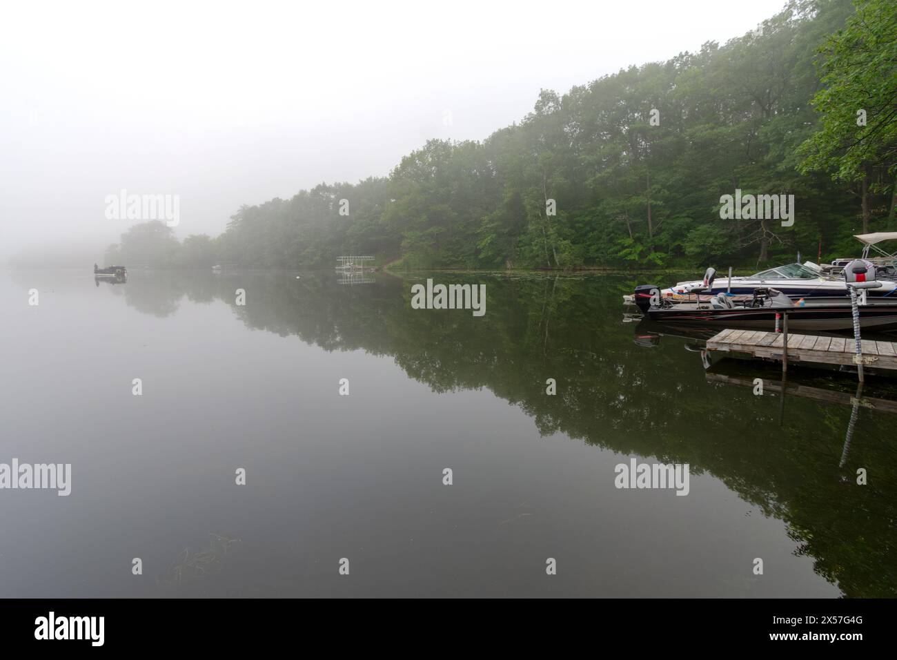 Blick auf einen ruhigen Wisconsin See an einem nebeligen Morgen. Fischerboot in der Ferne. Stockfoto
