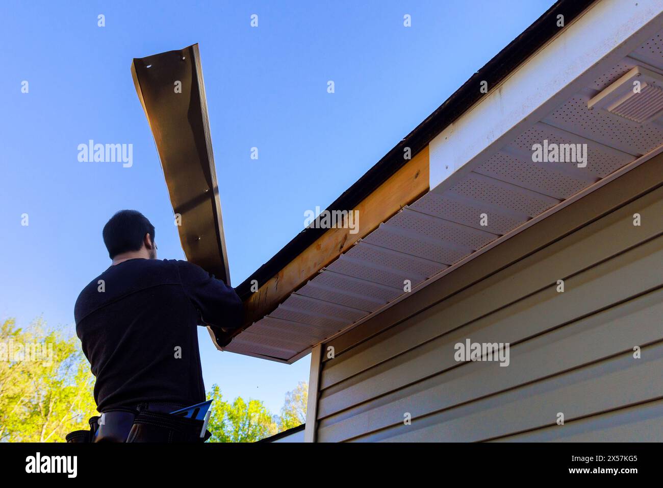 Der Meister führt Reparaturen durch, nachdem der Hurrikan dazu geführt hat, dass die Verkleidung der Aluminiumverkleidung abgeblasen wurde und freiliegendes Holz freiliegt Stockfoto