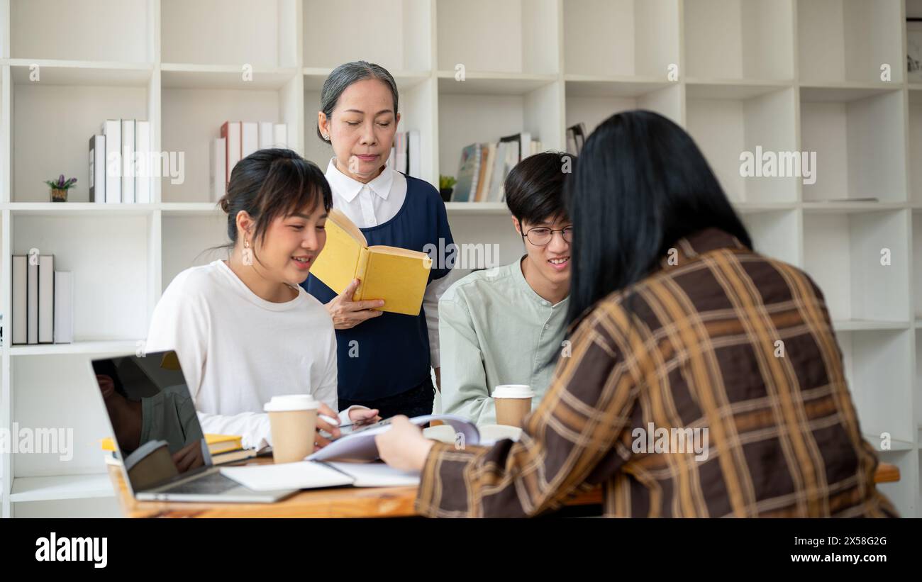 Eine strenge asiatische Professorin oder Lehrerin unterrichtet ihre Schüler im Klassenzimmer. Eine Gruppe von Studenten einer Universität, die mit einem Reifen f Stockfoto