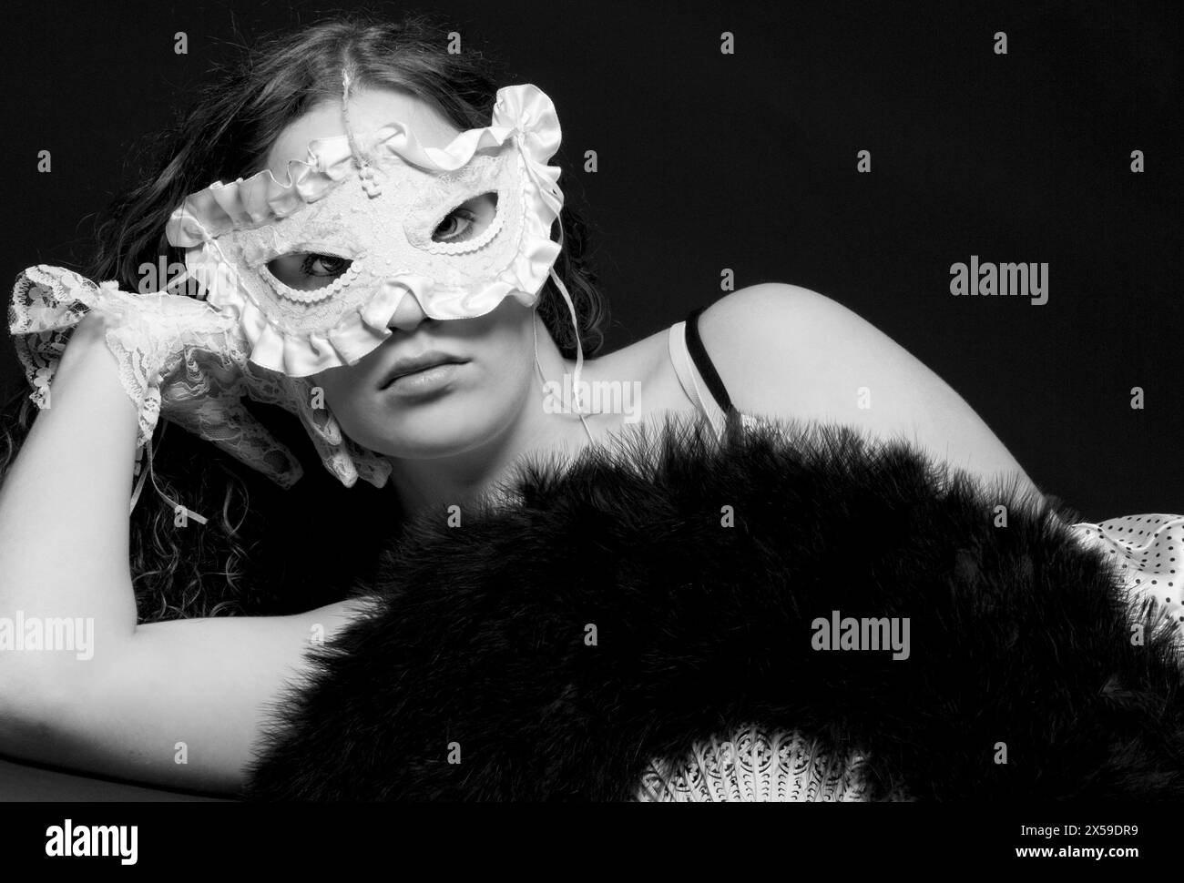 Porträt einer schönen jungen Frau, die Spitzenhandschuhe und Maske trägt, während sie in die Linse blickt, USA. Stockfoto