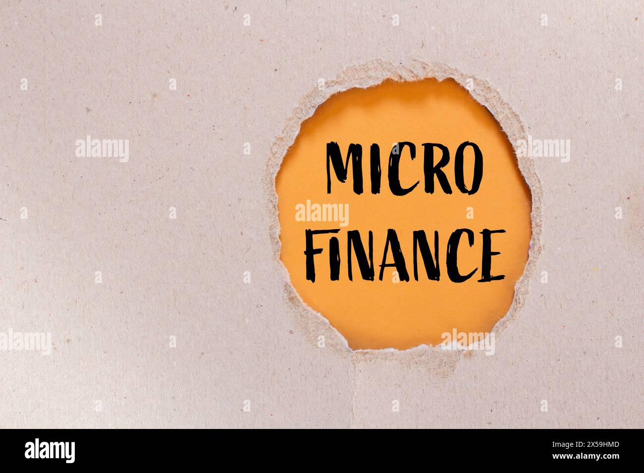 Wörter aus Mikrofinanzen auf zerrissenem Papier mit orangem Hintergrund. Konzeptionelles Geschäftssymbol für Mikrofinanzen. Kopierbereich. Stockfoto