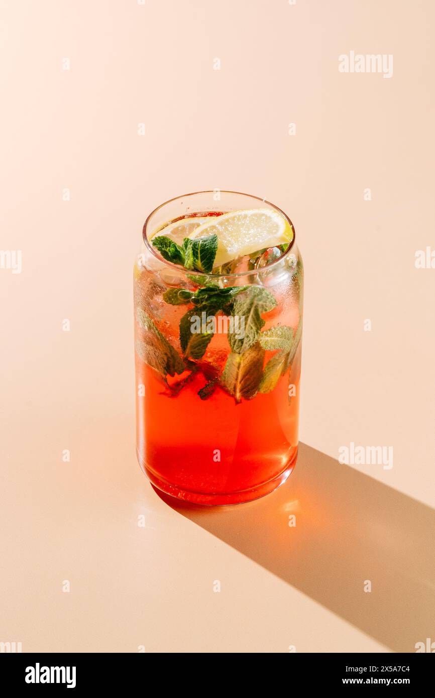Ein lebendiges Glas Beeren-Orange-Limonade garniert mit frischer Minze und einer Zitronenscheibe, perfekt für einen warmen Sommertag. Stockfoto