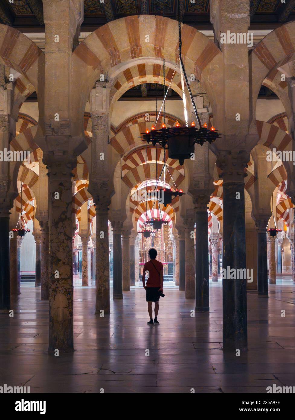 Ein einsamer Besucher kann die faszinierenden Bögen und Säulen in der historischen Großen Moschee von Cordoba bewundern, die die einzigartige Mischung aus Moo zeigt Stockfoto