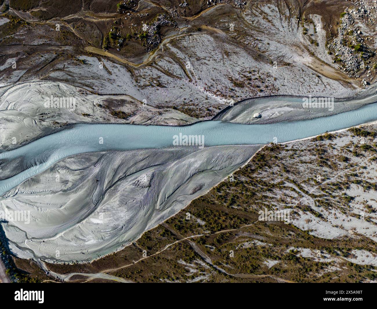 Hochauflösende Luftaufnahme mit einem geschwungenen Bergfluss, der durch eine strukturierte Landschaft mit abwechslungsreichem Gelände schlängelt Stockfoto