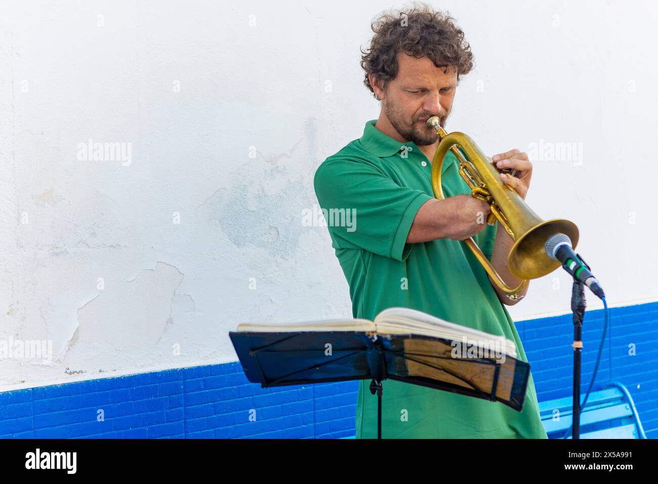 Ein einarmiger Mann spielt leidenschaftlich Trompete auf einer Straße der Stadt und bietet einen Inbegriff von Entschlossenheit und musikalischem Talent. Stockfoto