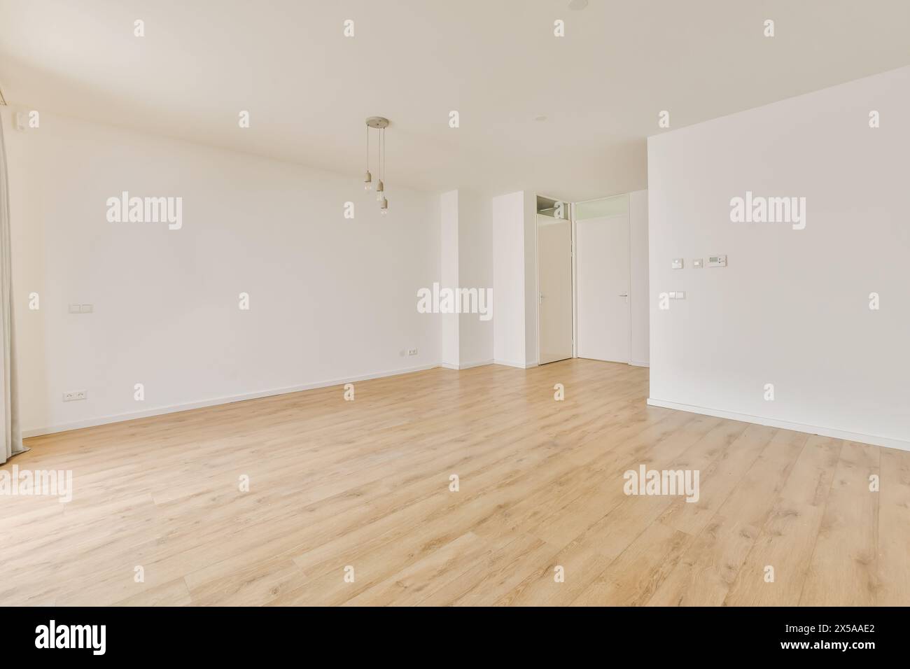 Ein leerer Innenraum mit einem hellen Raum mit natürlichem Holzfußboden, weißen Wänden und minimalistischer Ästhetik. Stockfoto