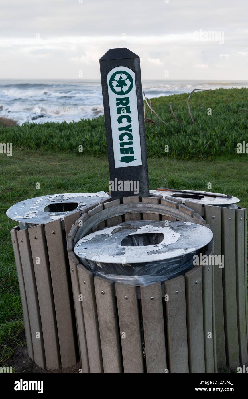 Mehrere Recyclingbehälter und Schilderpfosten auf einem grasbewachsenen Feld am Ufer des Pazifischen Ozeans in Nordkalifornien. Stockfoto