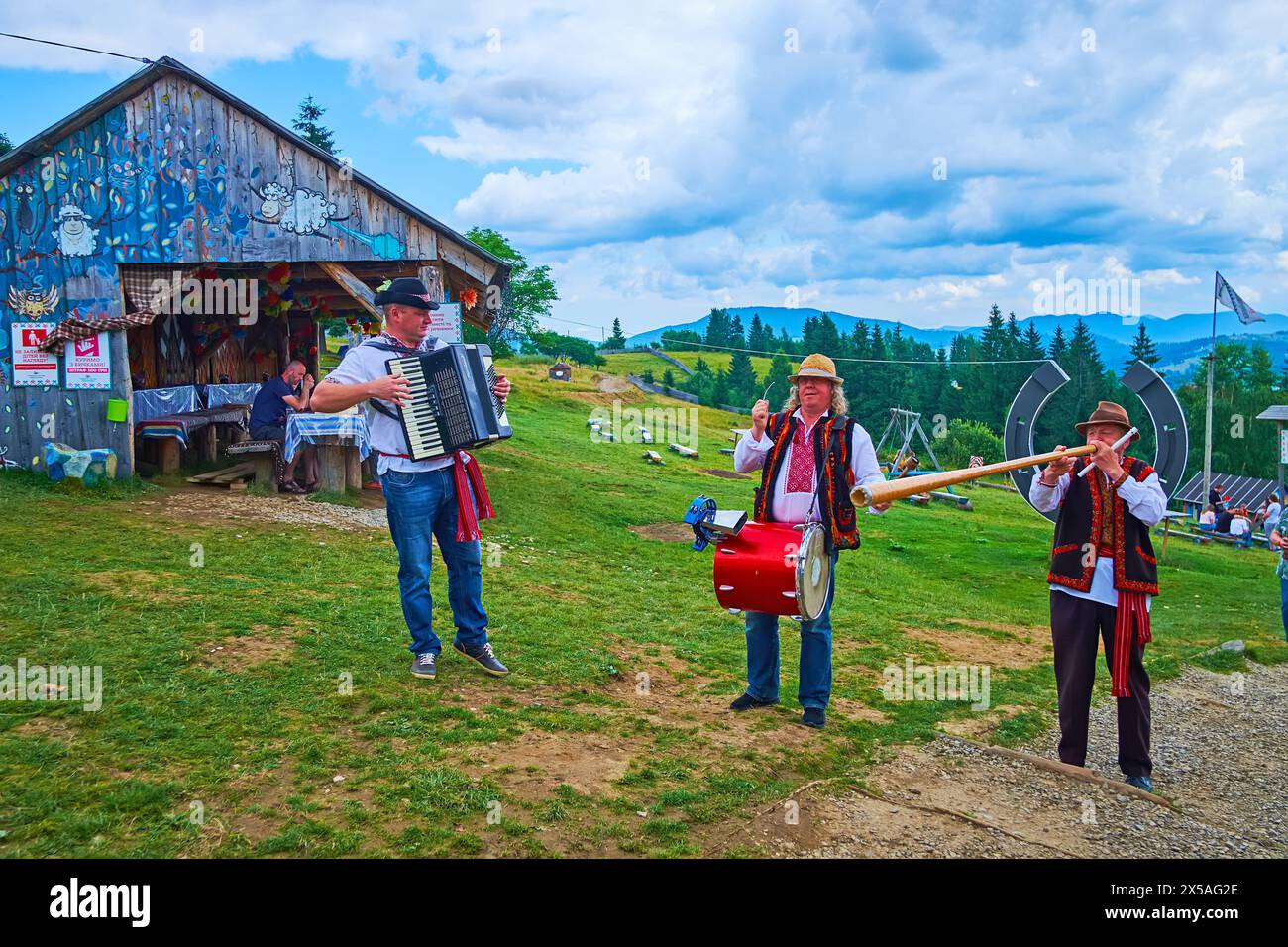 YABLUNYTSYA, UKRAINE - 24. JULI 2021: Die Folklore mit traditionellen Musikinstrumenten (Akkordeon, Trommel und Trembita-Alpenhorn) spielt auf dem Berg Stockfoto