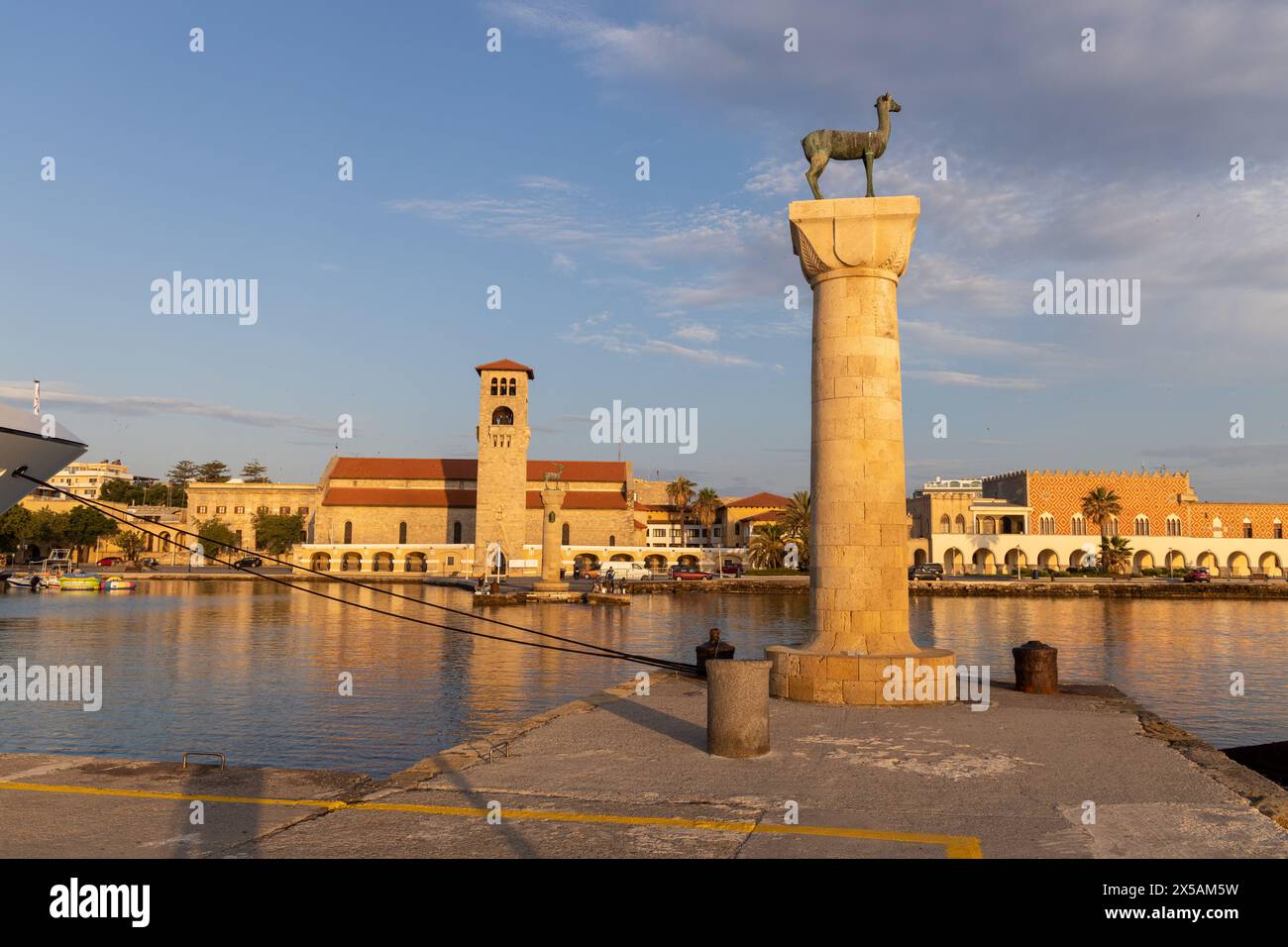 Rhodos, Griechenland - 12. Juni 2023: Bucht zum Hafen von Rhodos mit mittelalterlicher Statue und Häusern in der Morgensonne. Stockfoto