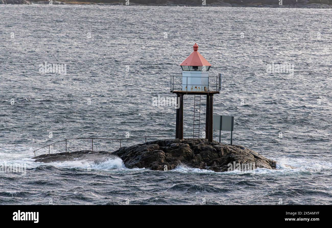 Vor der Küste Norwegens tobt ein Sturm, das Wetter im norwegischen Meer ist stürmisch, die Natur rau. Ein kleiner Leuchtturm zeigt den Schiffen den ric Stockfoto