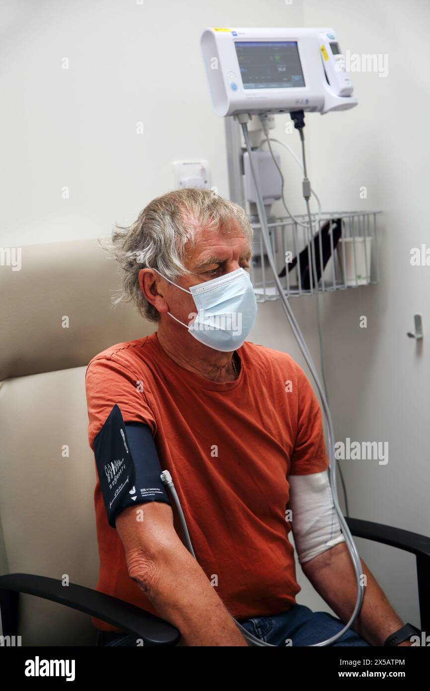 Patient mit Gesichtsmaske, der vor der Chemotherapie im Hospital Surrey England den Blutdruck untersucht hat Stockfoto