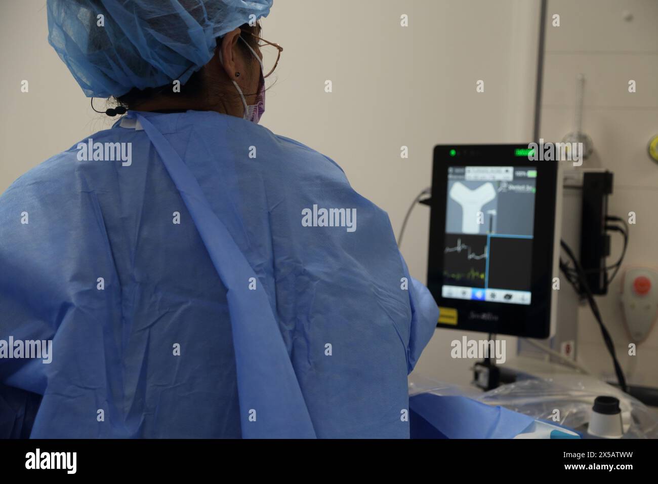 Monitor der Pflegekraft während der Verabreichung von Peripheral eingeführtem Zentralkatheter (Picc Line) unter Lokalanästhesie im Krankenhaus Surrey E Stockfoto