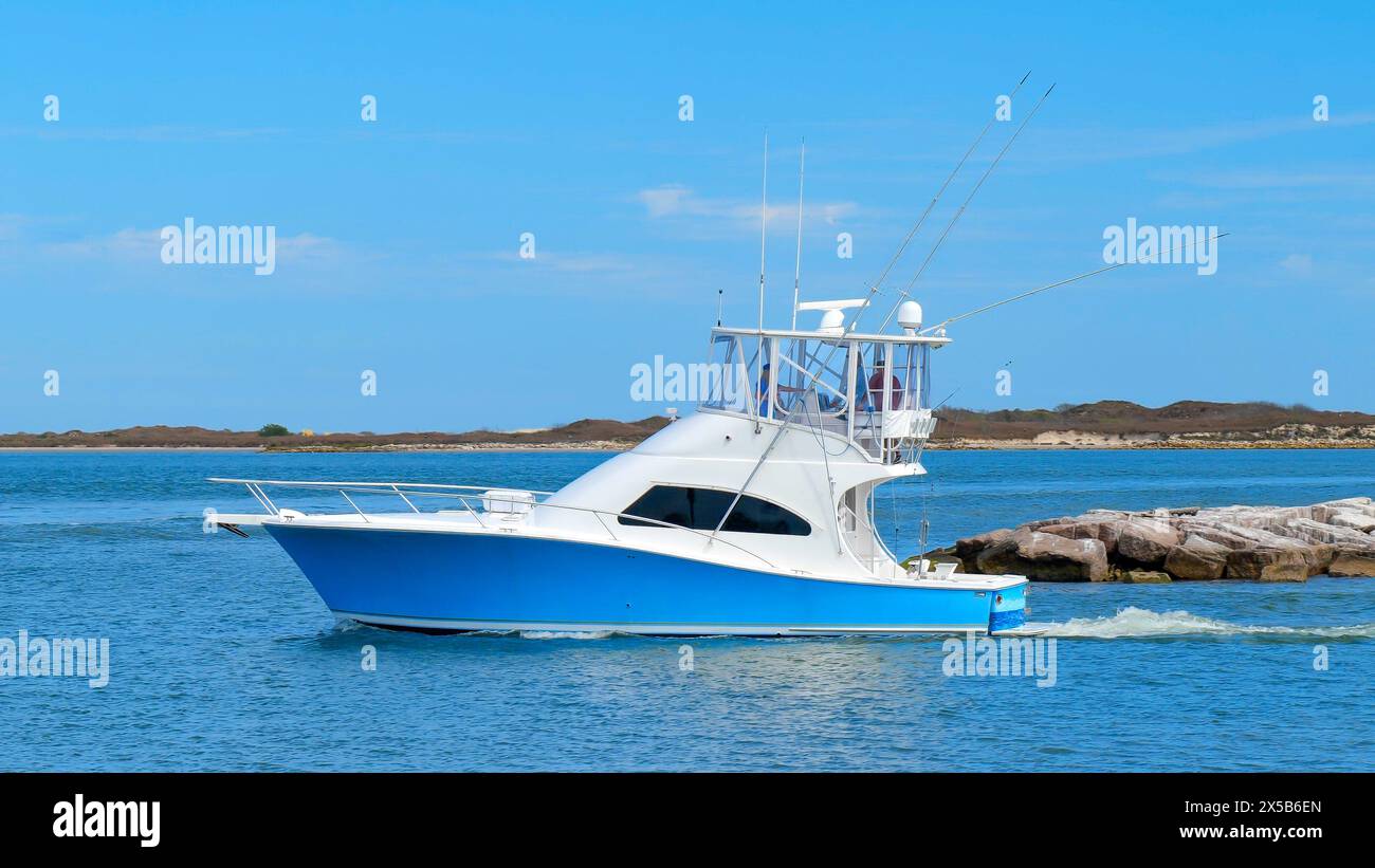 Ein wunderschönes blau-weißes Fischerboot segelt auf dem ruhigen blauen Wasser, während es an einem sonnigen Tag den Yachthafen verlässt. Stockfoto