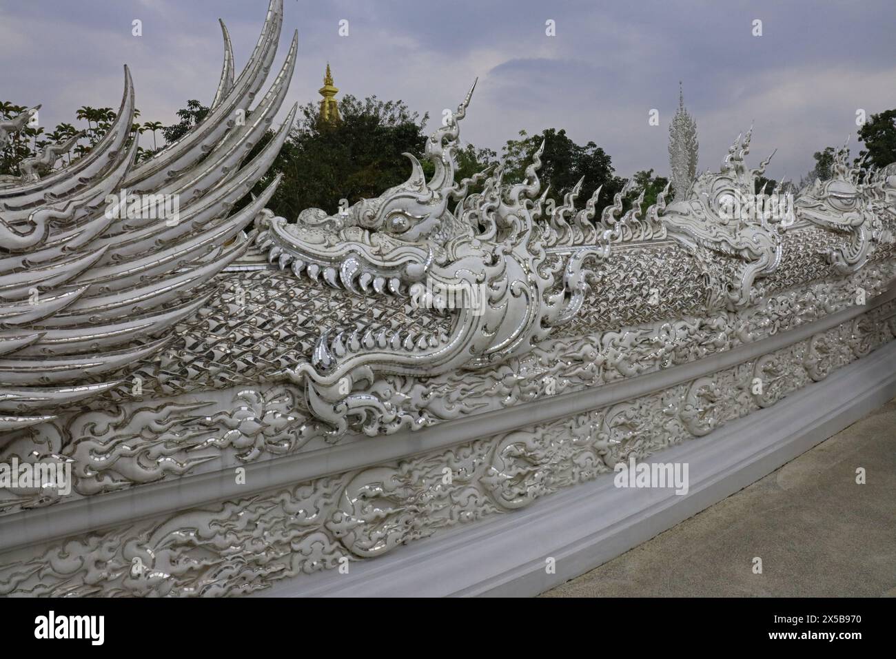 Eine Statue eines Drachen, der das Ende des Drachen vor ihm auf der Brücke zum Weißen Tempel in der Provinz Chiang Rai, Thailand, isst Stockfoto