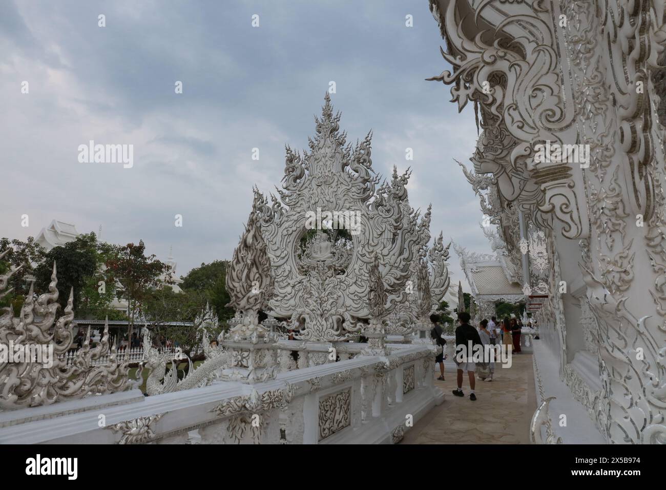 Komplizierte und aufwendige Schnitzereien am Weißen Tempel in Thailand mit Touristen, die herumlaufen Stockfoto