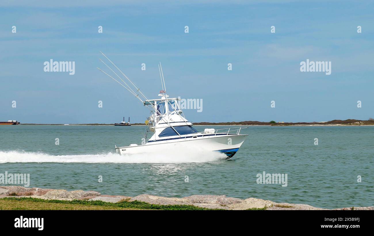 Das wunderschöne weiße Fischerboot segelt auf dem ruhigen blauen Wasser, wenn es sich an einem sonnigen Tag der Marina nähert. Stockfoto